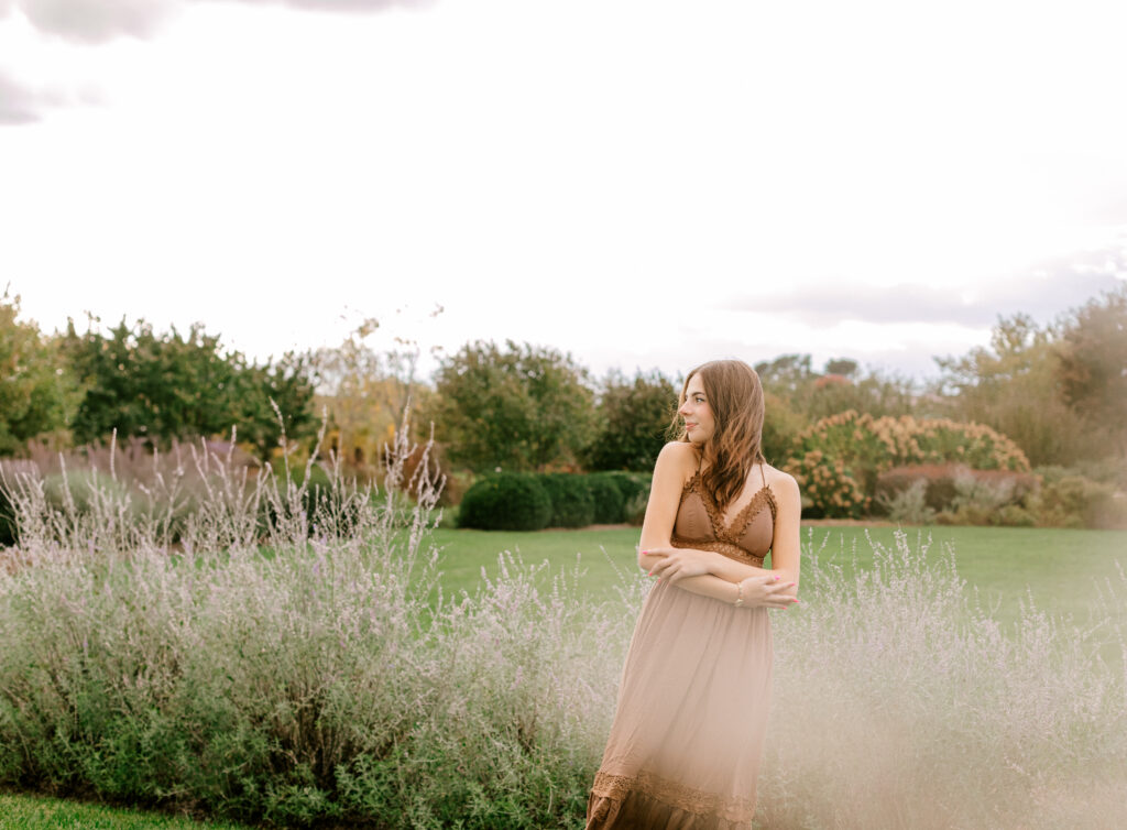 Senior girl in a soft brown dress standing in a lavender field during golden hour in Virginia